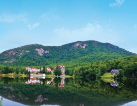 The historic Balsams Grand Resort Hotel, with its iconic red roof, reflected in Lake Gloriette.