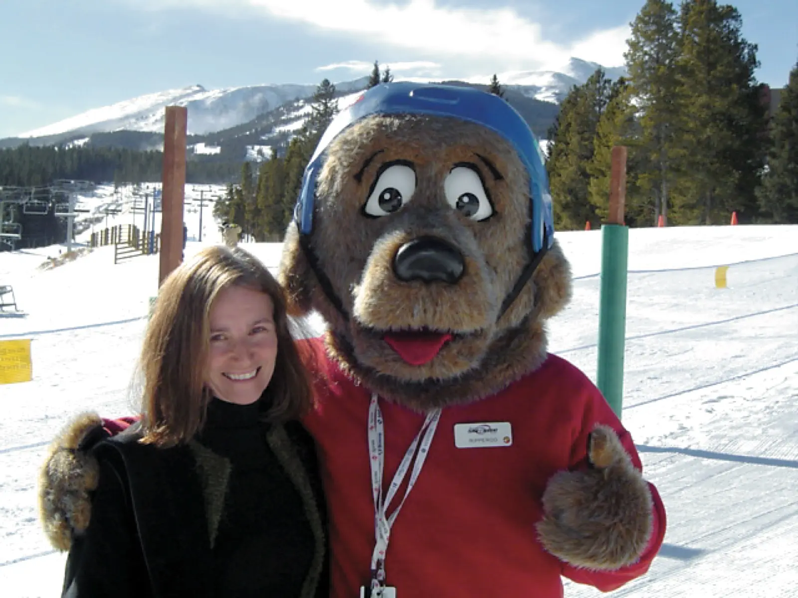 Lucy Kay smiling beside a bear mascot on a ski slope