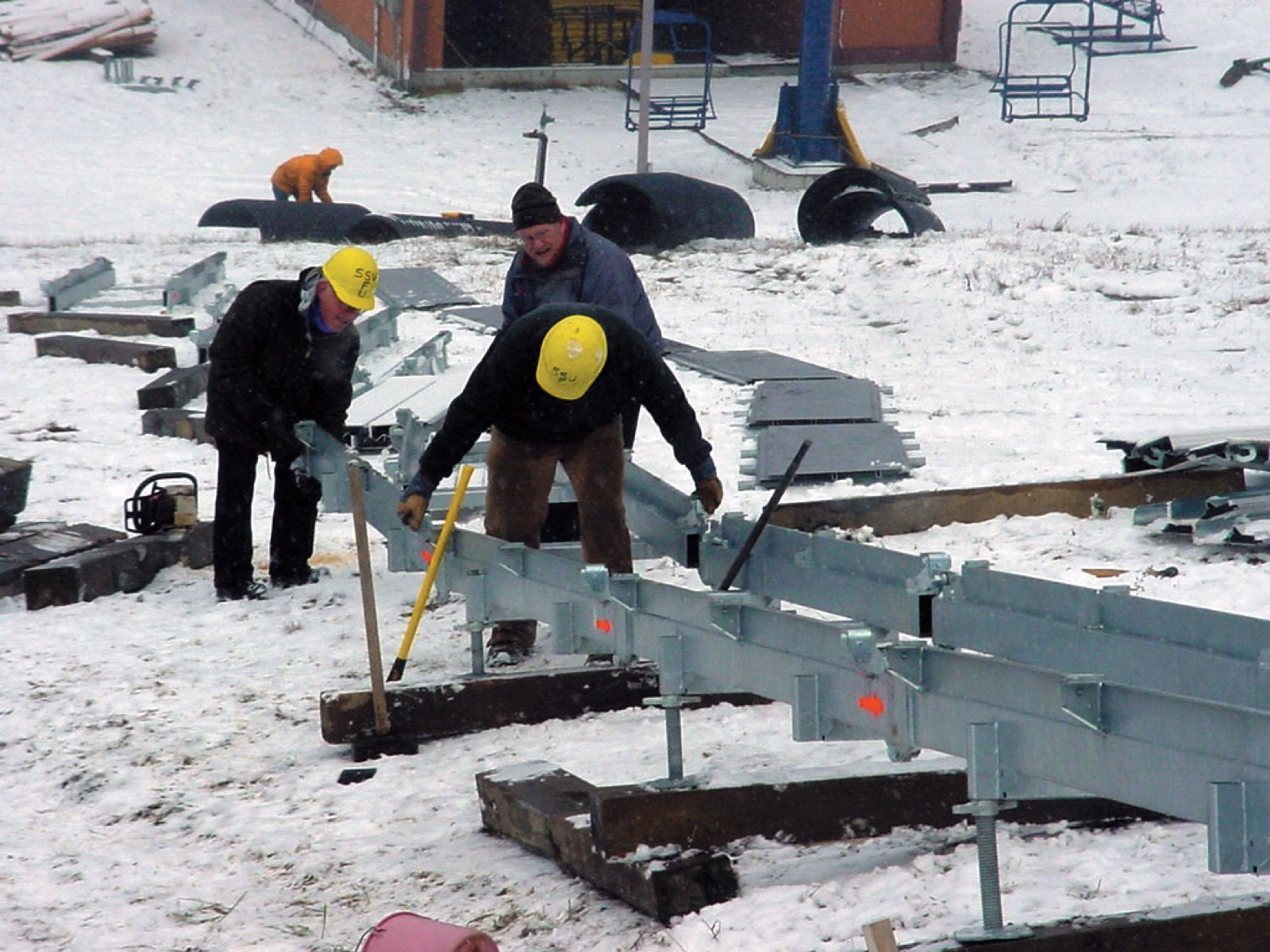 Crew assembling a conveyor lift frame in the snow