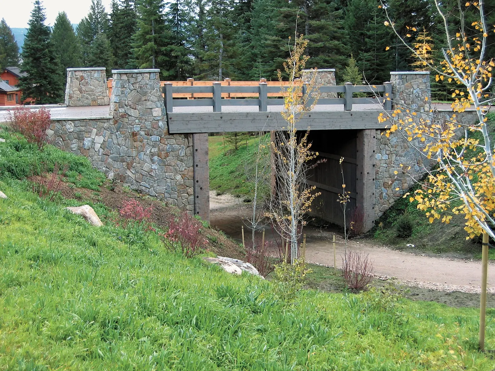 Stone-faced ski bridge over a path among aspens
