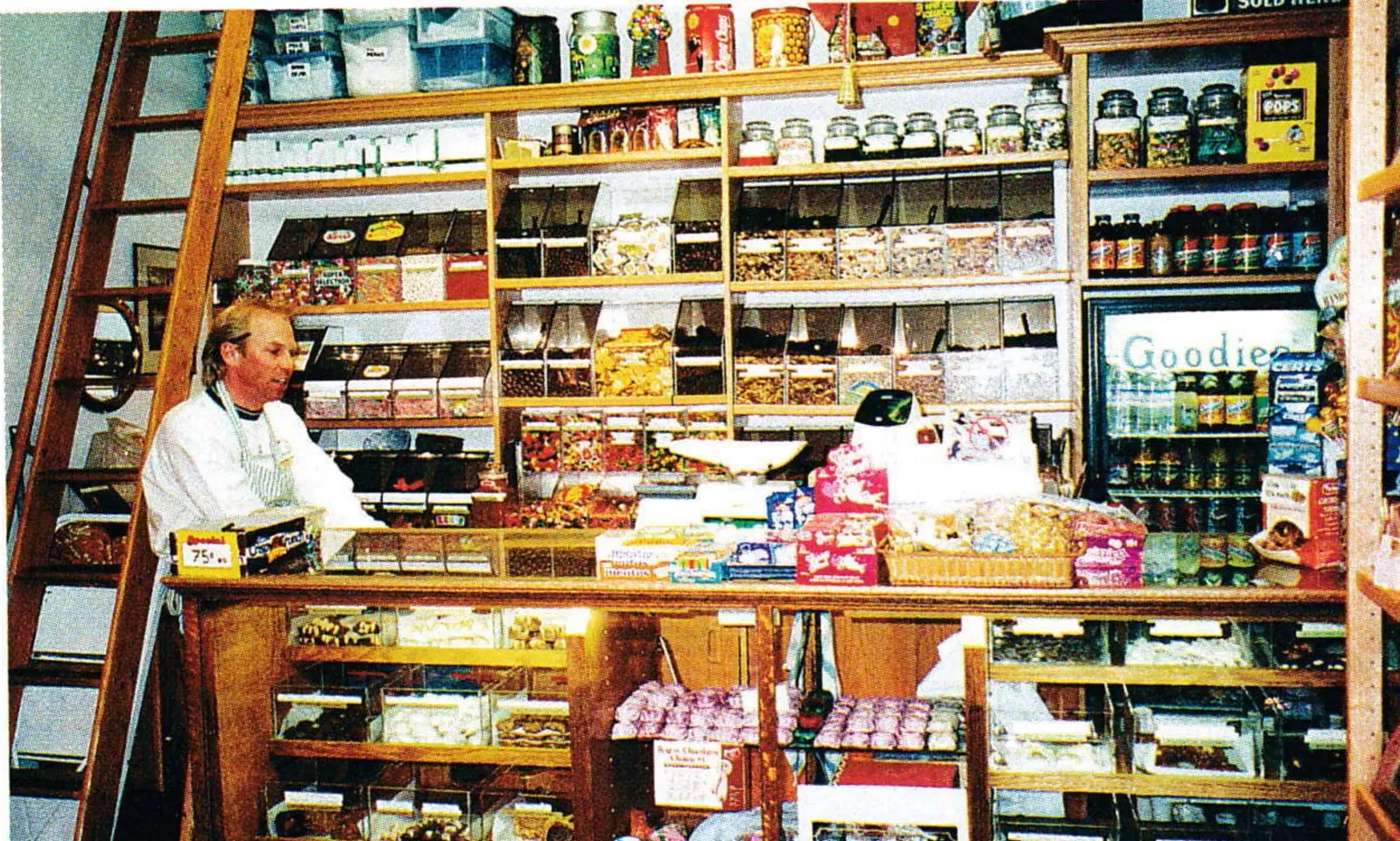 Shopkeeper behind a wooden counter in an old-fashioned general store with shelves stocked floor to ceiling