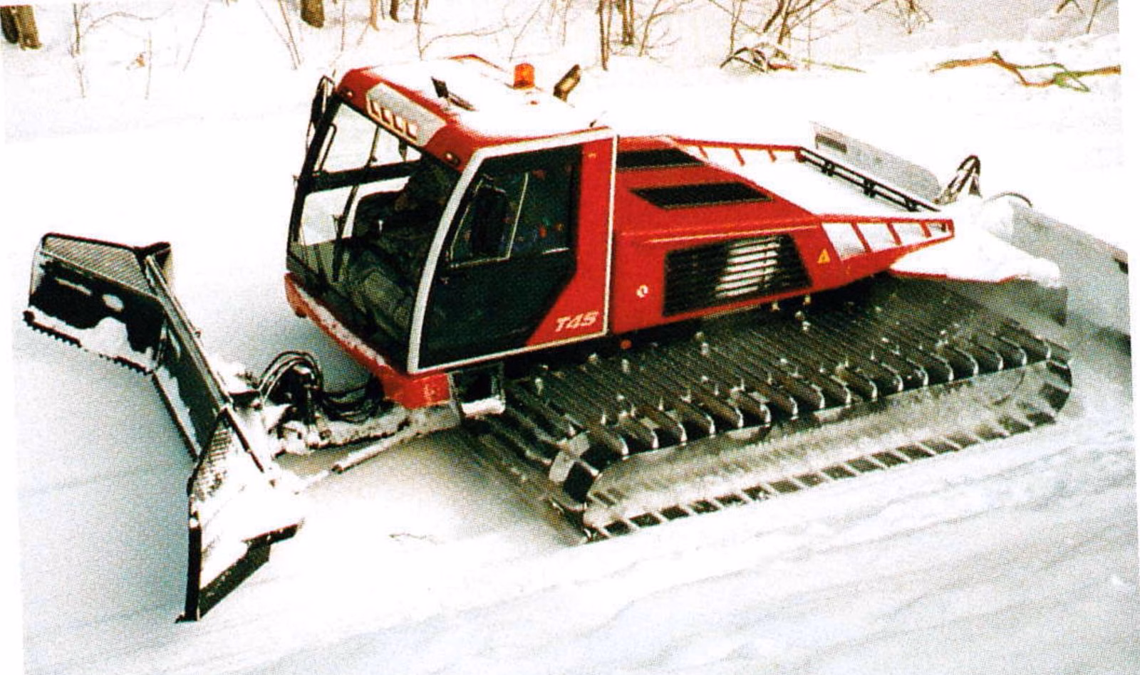 Red Prinoth T4-S groomer with front blade working on a snowy slope