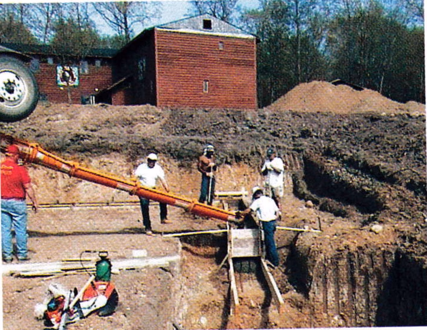Workers pouring concrete into foundation forms from a conveyor