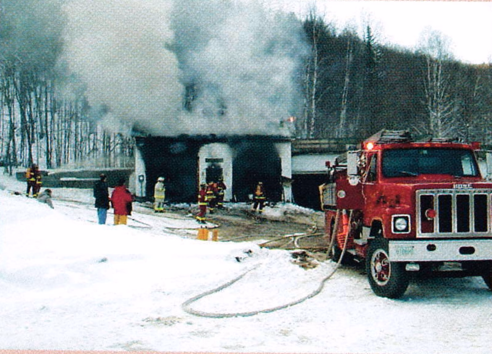 Fire trucks and firefighters at the smoking Jackson Ski Touring maintenance shed in winter