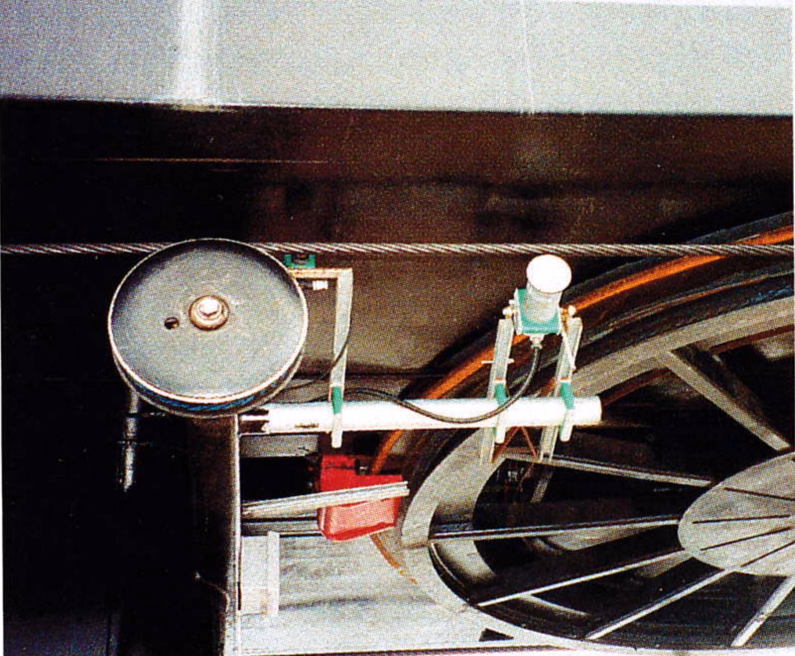 Small white tachometer wheel mounted beside the haul rope behind a lift guide sheave near the bullwheel