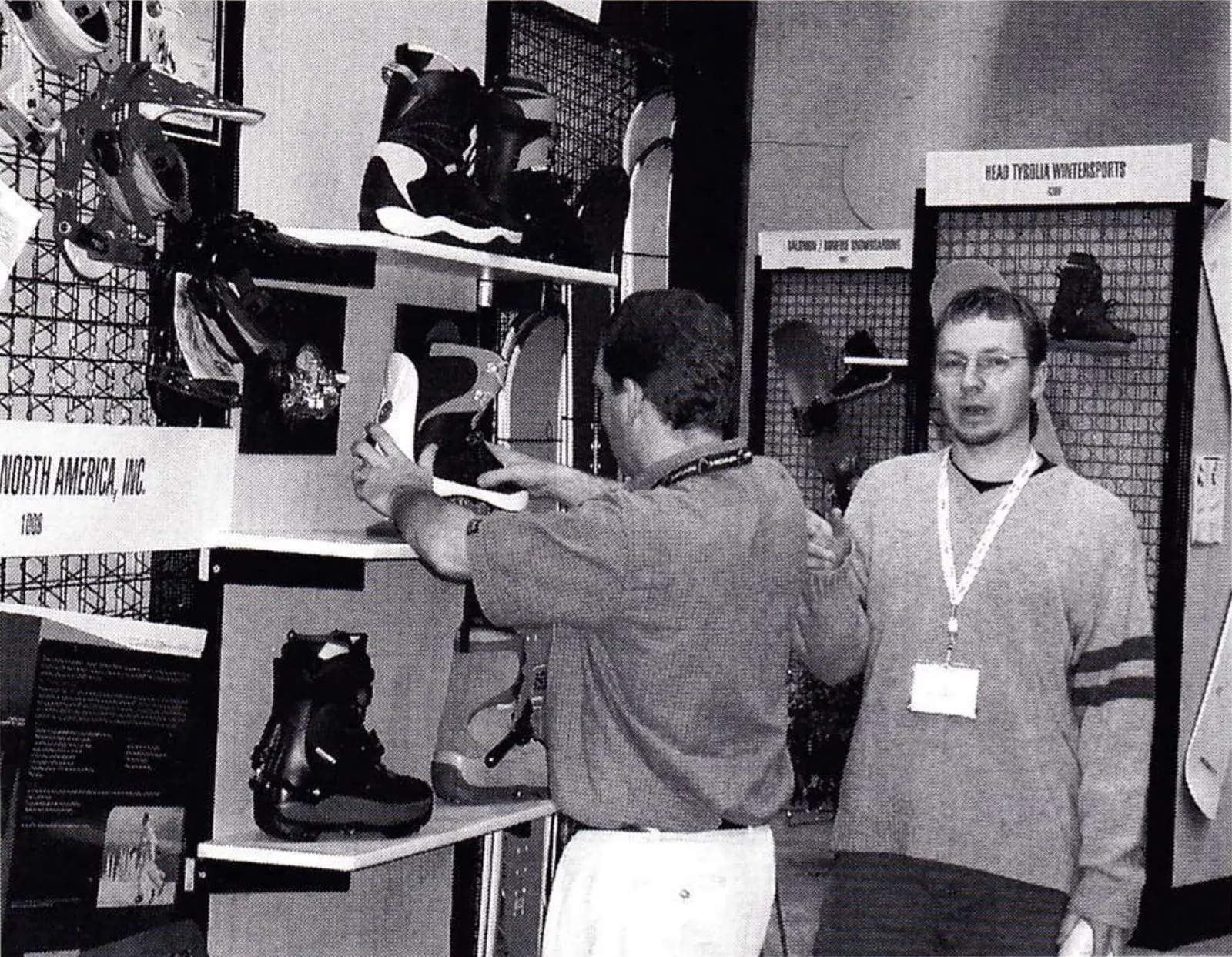 Trade-show booth with rental boots on shelves as two men talk in Rental Alley at the SIA show