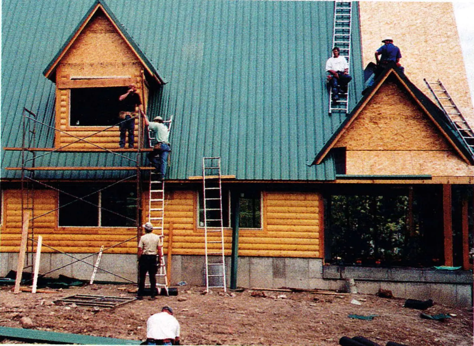 Volunteers on scaffolding and a ladder working on the log-sided patrol building under construction