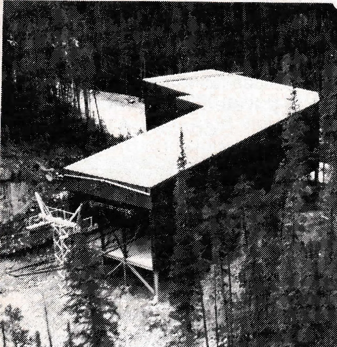 This Curve Station turns Section I through 63°. On each side of the rope is a launcher and a decelerator. Up-bound cabins pass just clear of the cliff visible to the left of the building. In the background can be seen the road which this gondola replaces.