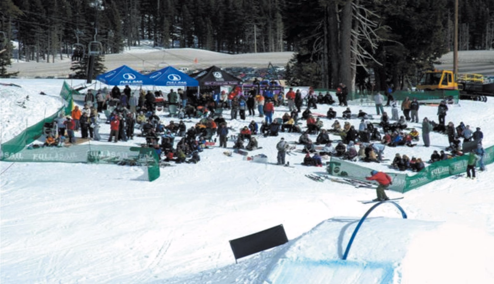 Crowd watching a rail jam beside tents in the learning area