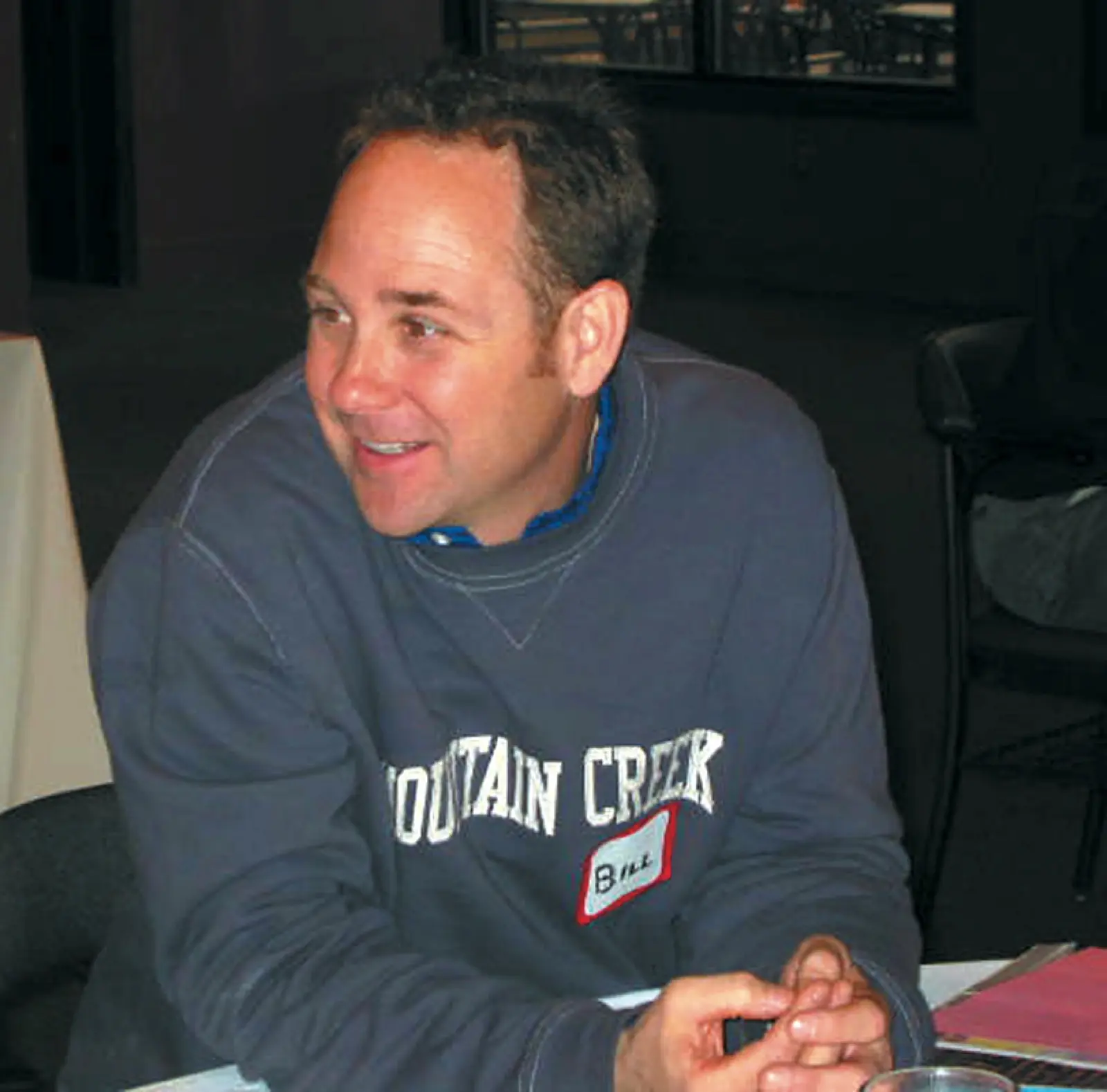 Bill Benneyan smiling at a table in a Mountain Creek sweatshirt