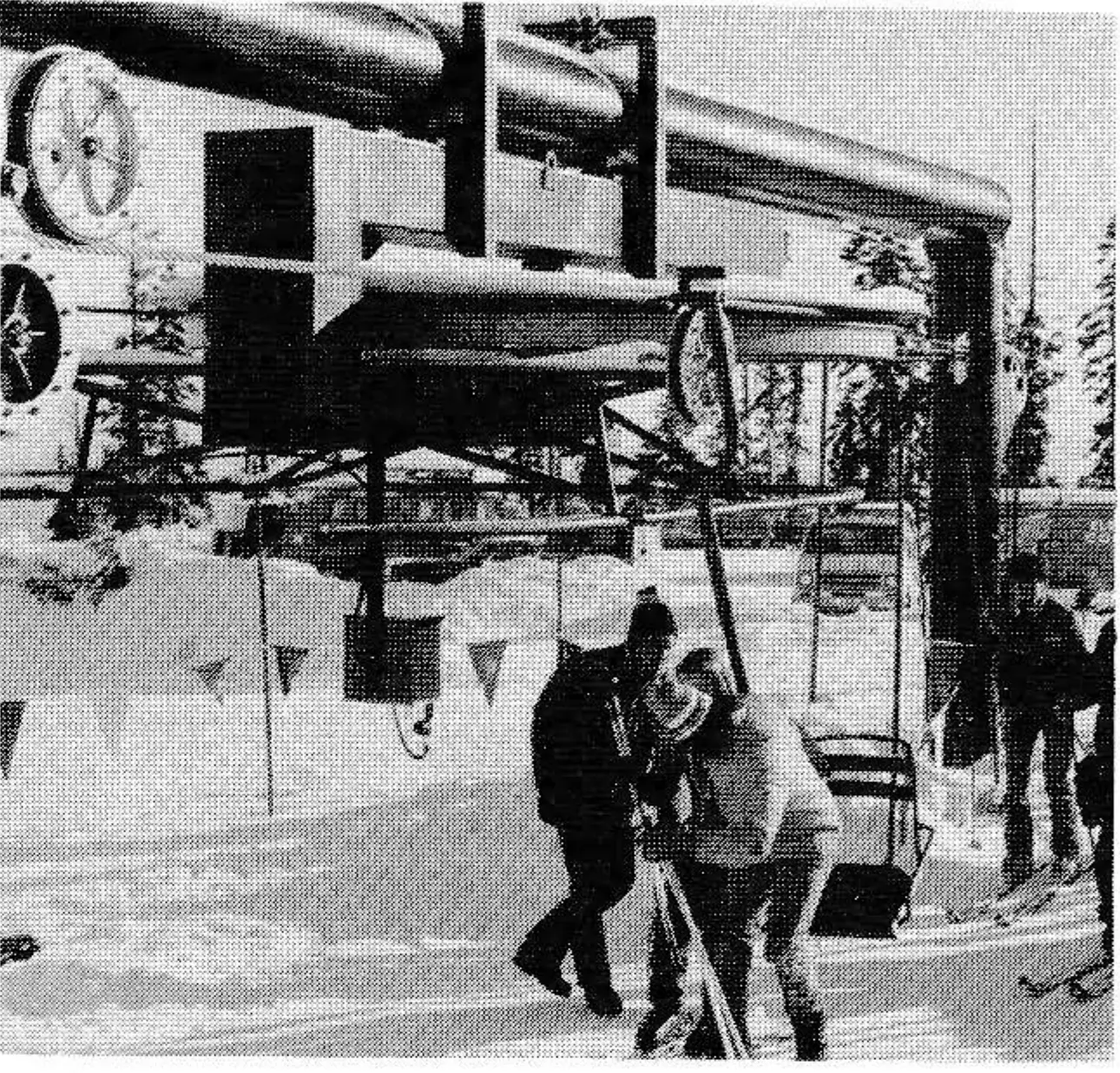 The lower terminal (left) is designed so it can be used as a bullwheel loading or conventional loading unit, whichever is desired. The counterweight is located in a pit immediately behind the rearward vertical column of the tension terminal structure, thus allowing the skiers to approach the loading point in a straight line from the rear.