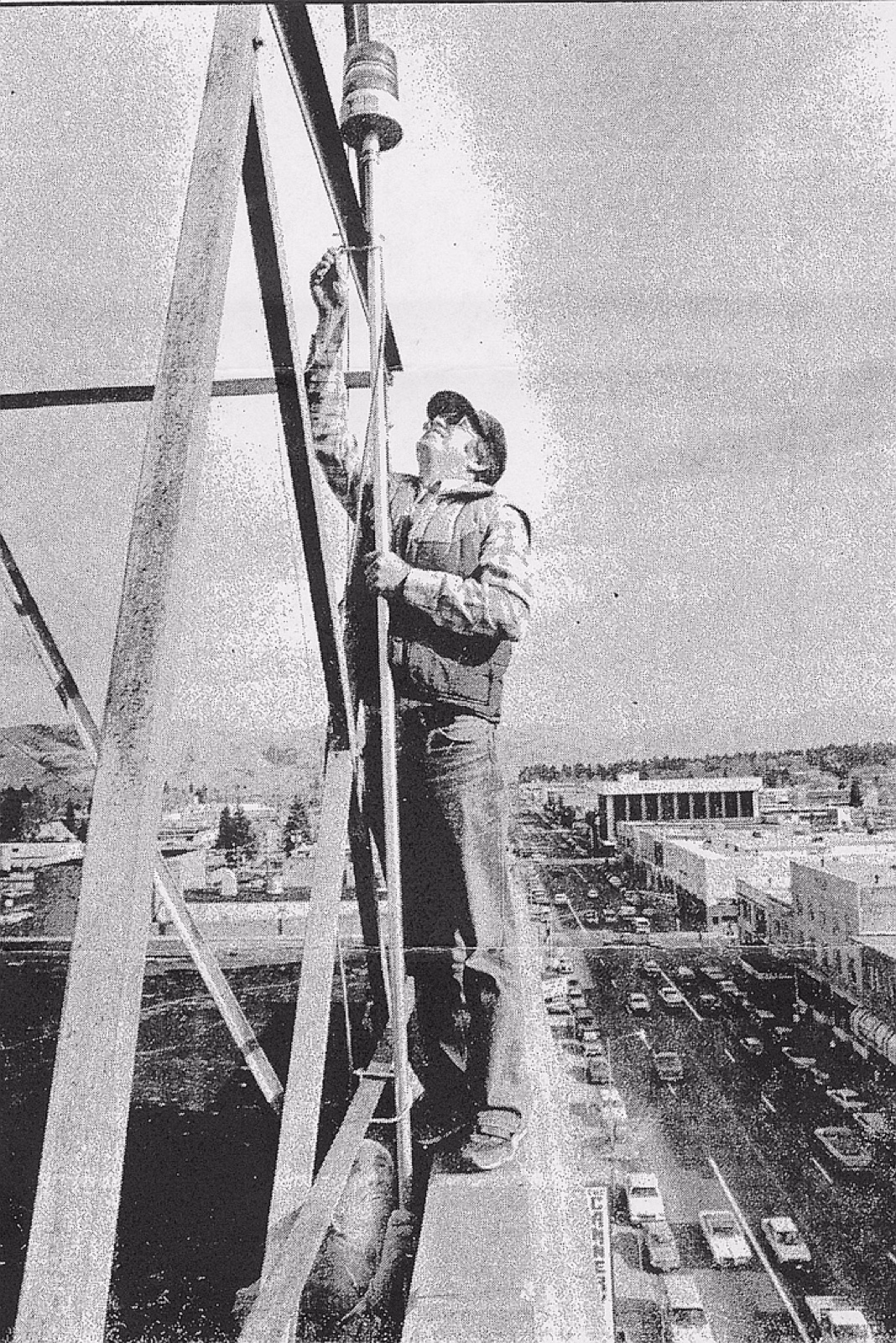 Worker climbing a beacon tower above a town